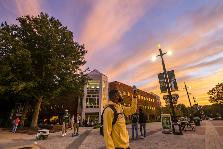 students outside the Johnson Center at sunset
