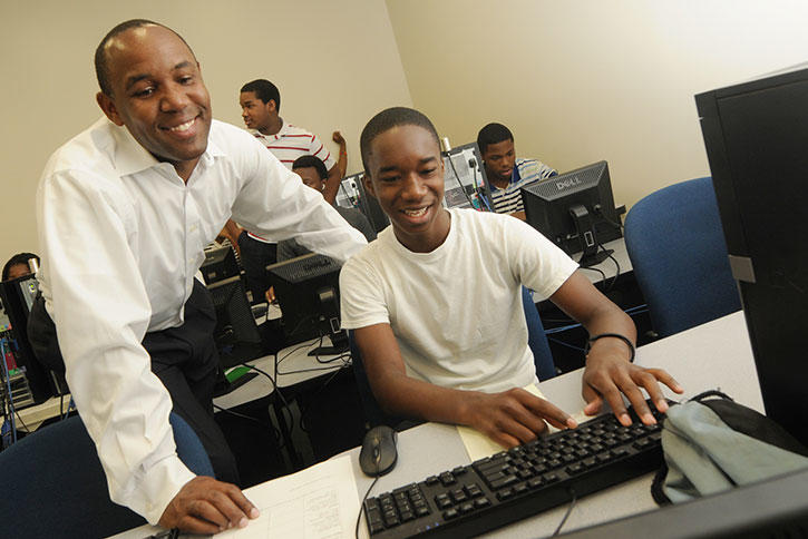 Dr. Kevin Clark helps a student on a computer at Mason