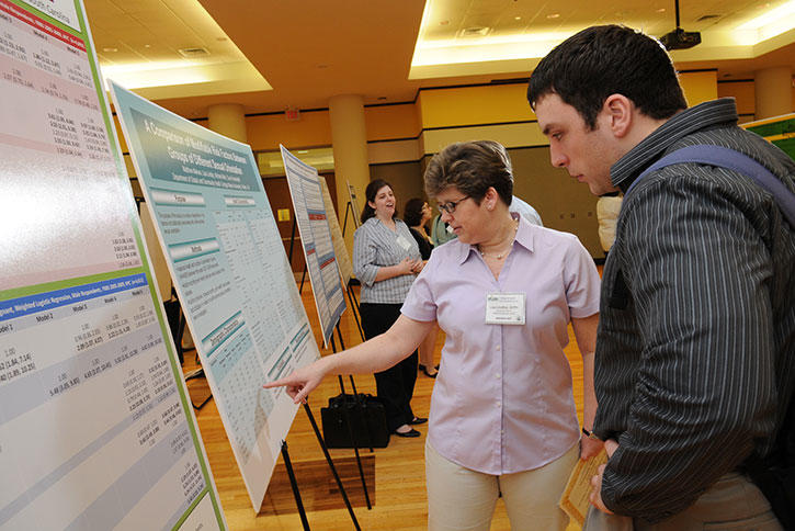 Lisa Lindley talks to a student at a poster display at Mason