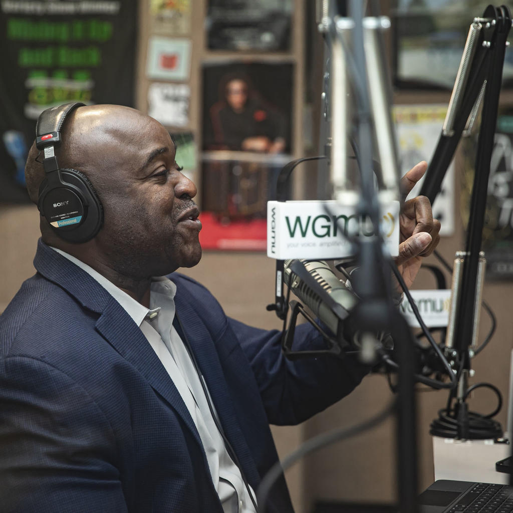 Mason President Gregory Washington sits in an audio studio with a headset speaking into a microphone